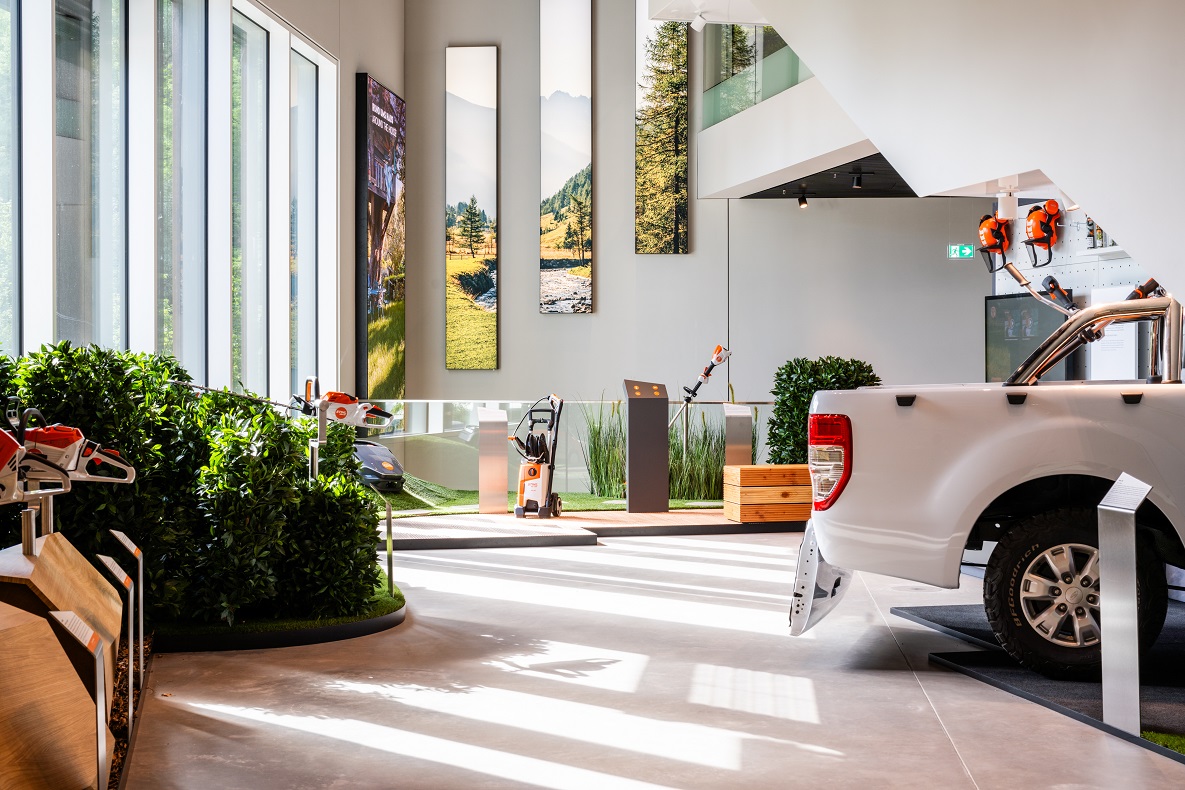 A modern presentation room in the STIHL Brand World with visitors, a large light circle, and nature-themed motifs in the background.